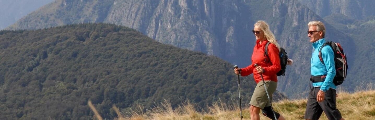 Two walkers with trekking poles on a mountain ridge